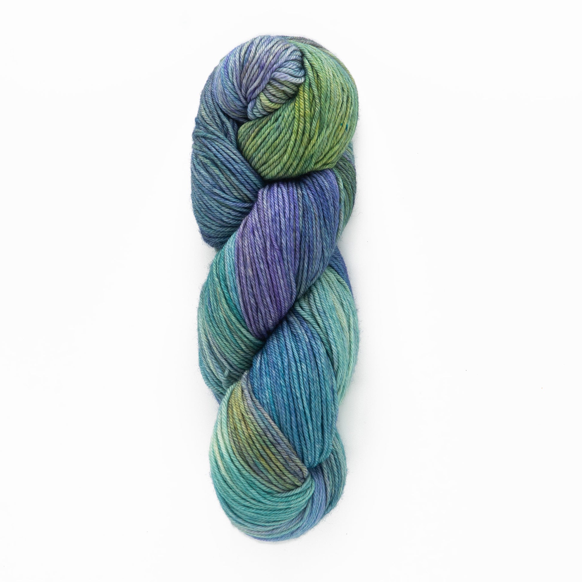 A skein of Malabrigo Arroyo yarn from Malabrigo Yarn is twisted into an oval shape. This sport weight superwash merino wool boasts a gradient of colors, seamlessly blending shades of green, blue, and purple. The colors smoothly merge to create a visually pleasing, multicolored effect against a plain white background.