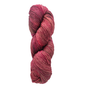 A tightly wound skein of Malabrigo Arroyo yarn in pink and red hues, isolated against a white background. The Malabrigo Yarn brand offers a palette with varying shades that enhance the textured appearance of the superwash merino wool.