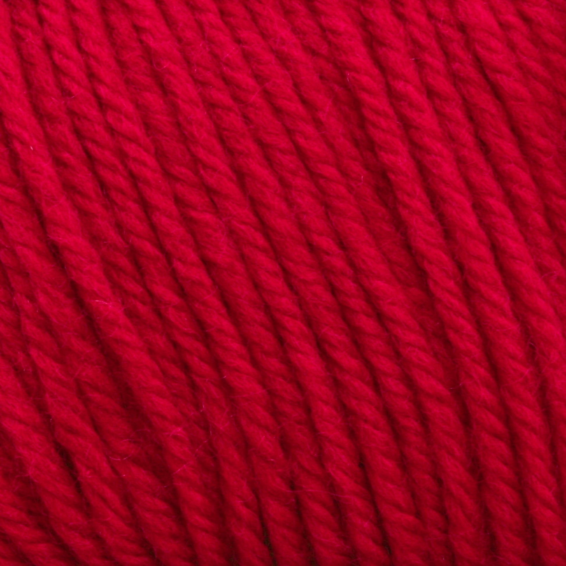 Close-up of bright red Cascade 220 Superwash Wool Yarn from Cascade Yarns, showcasing its smooth and tightly twisted strands. The texture appears soft and slightly fuzzy, with the 100% merino wool fibers tightly wound together in a uniform pattern. The vibrant color is consistent throughout, offering beautiful stitch definition.