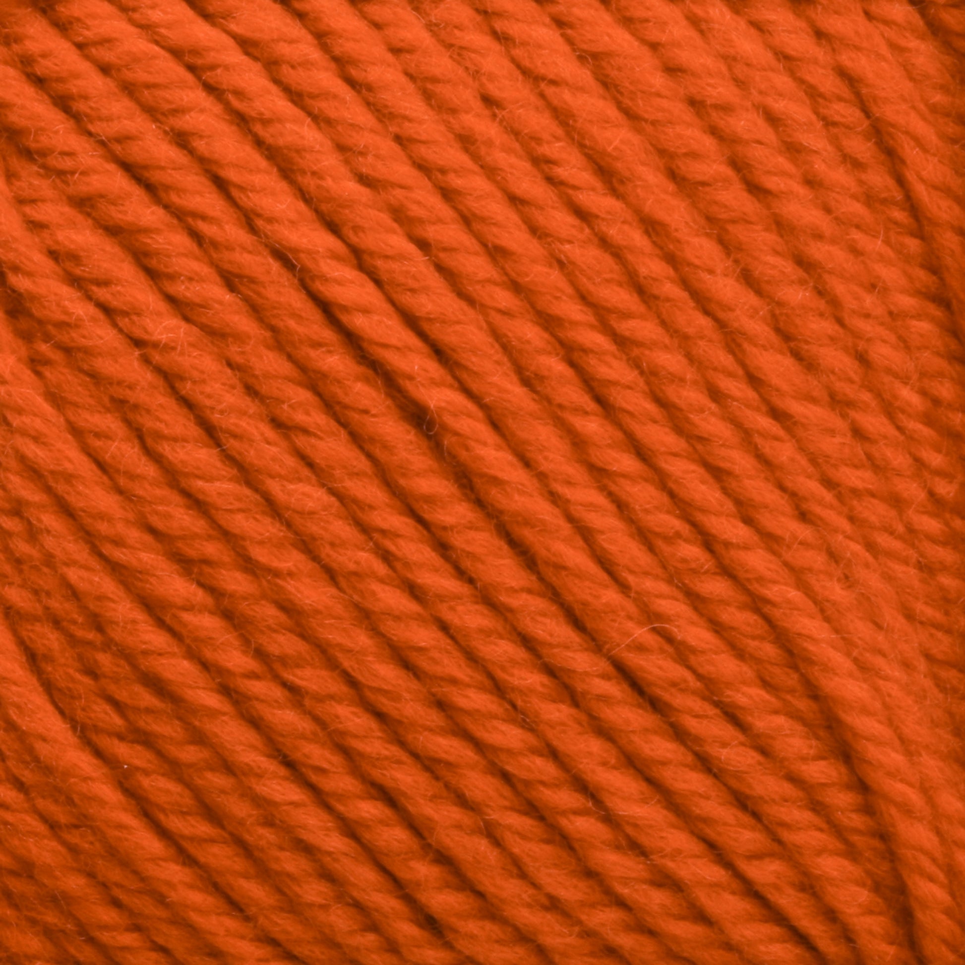 Close-up of Cascade 220 Superwash Wool Yarn in orange, showcasing tightly wound strands. The 100% merino wool texture from Cascade Yarns appears soft, with visible twists in the fiber, offering beautiful stitch definition. Suitable for knitting or crocheting projects.