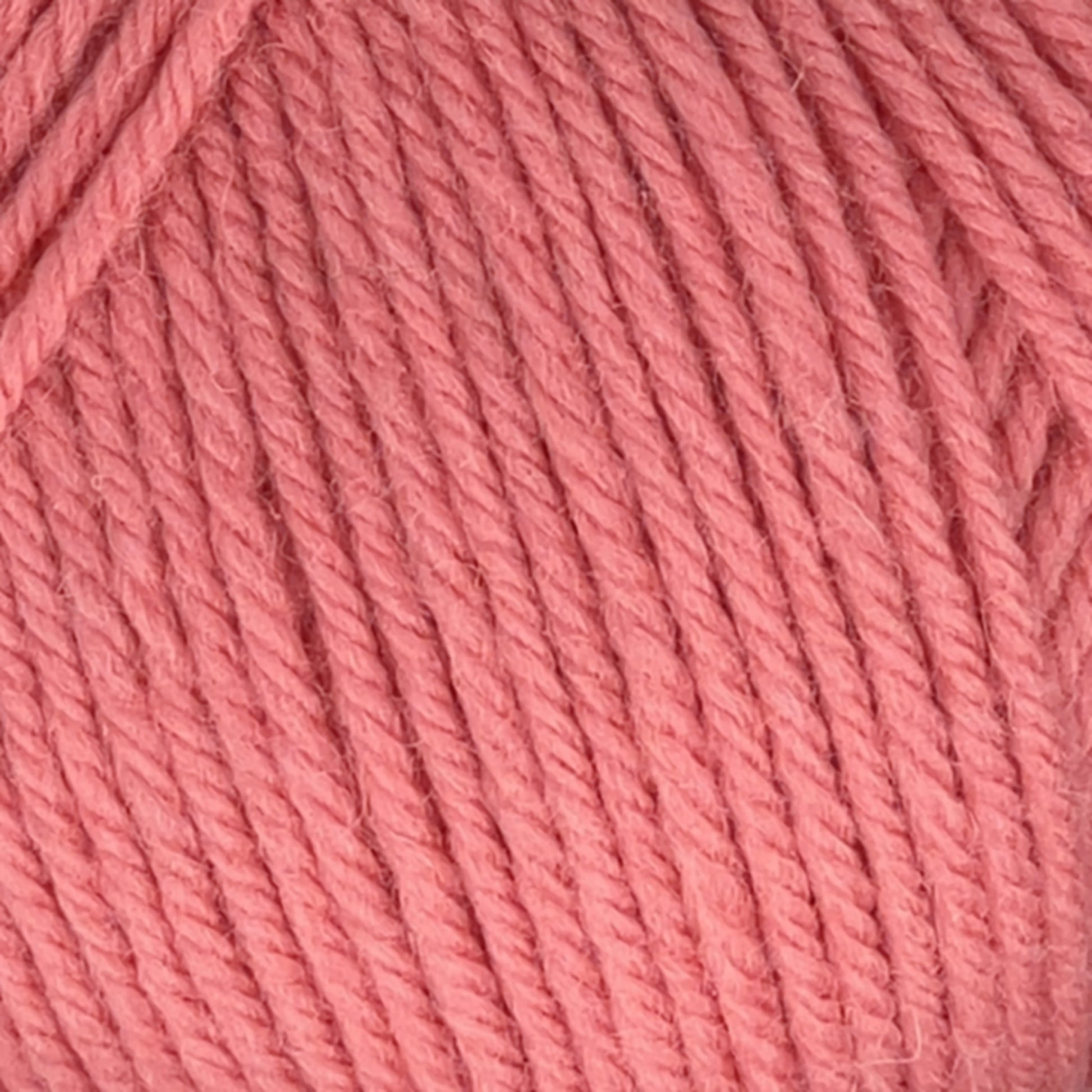 Close-up of Cascade 220 Superwash Wool Yarn in a coral color, made from 100% merino wool by Cascade Yarns. The texture and individual strands are tightly wound together, providing beautiful stitch definition. This superwash DK weight yarn appears soft and smooth, perfect for knitting or crochet projects.