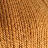 Close-up image of a ball of light brown Cascade 220 Superwash Wool Yarn by Cascade Yarns. The slightly coarse texture with visible individual strands twisted together showcases a beautiful stitch definition. The color is uniform throughout, and some fibers are gently sticking out from the surface, highlighting the quality of this 100% merino wool yarn.