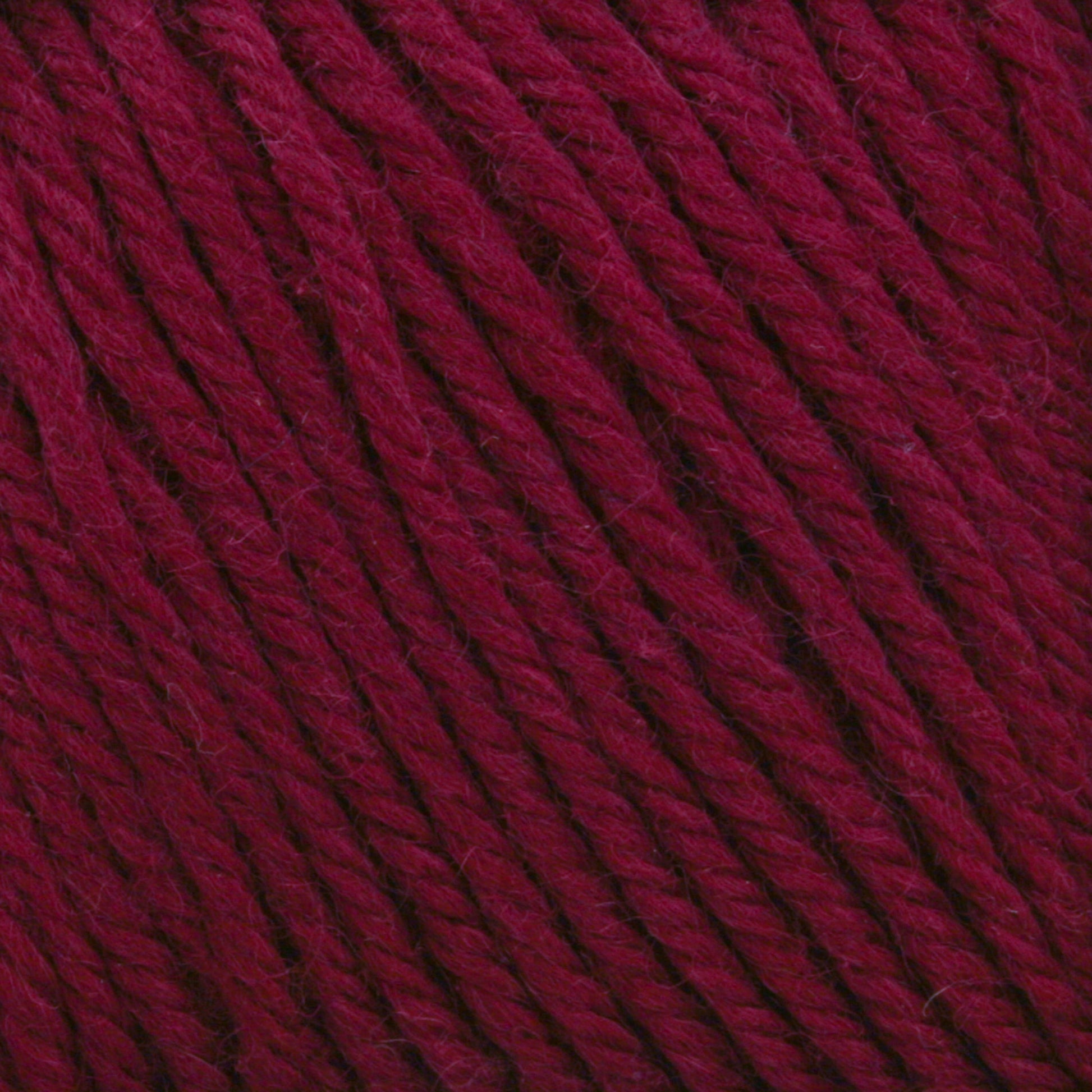 Close-up of Cascade 220 Superwash Wool Yarn in burgundy, showcasing its twist and texture. The rich, deep red 100% merino wool fibers are tightly wound, highlighting the intricate details and beautiful stitch definition. The yarn appears soft and thick, suitable for knitting or crocheting.