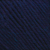 Close-up of a ball of Cascade 220 Superwash Wool Yarn by Cascade Yarns in deep blue and purple, showcasing the detailed texture of the tightly wound strands. The 100% merino wool fibers vary slightly in shade, giving the DK weight yarn a rich, multidimensional appearance, perfect for beautiful stitch definition.