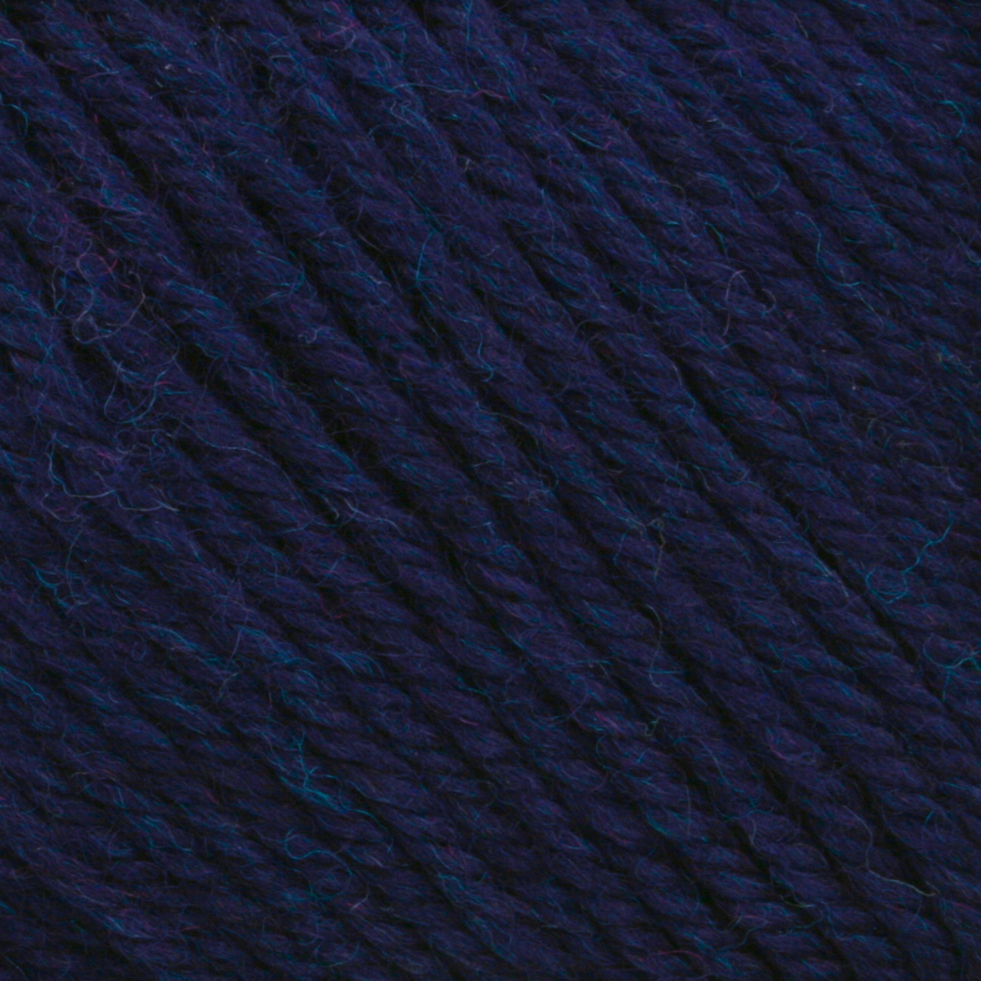 Close-up of a ball of Cascade 220 Superwash Wool Yarn by Cascade Yarns in deep blue and purple, showcasing the detailed texture of the tightly wound strands. The 100% merino wool fibers vary slightly in shade, giving the DK weight yarn a rich, multidimensional appearance, perfect for beautiful stitch definition.