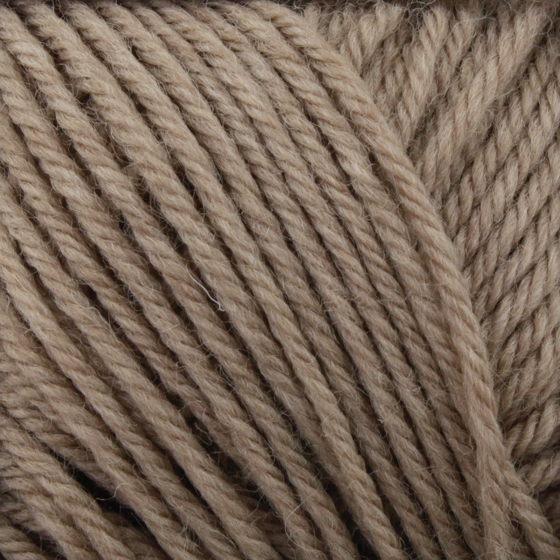 Close-up of light brown yarn strands tightly wound together. The texture shows the individual fibers making up this 100% merino wool Cascade 220 Superwash Wool Yarn by Cascade Yarns, emphasizing its softness and beautiful stitch definition.