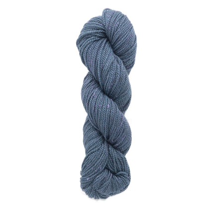 A twisted skein of Acadia by The Fiber Company yarn in dark blue with a subtle tweed effect and lighter streaks is neatly arranged against a plain white background. The yarn, offered by The Fibre Co. (UK) Ltd, appears soft and thick, suitable for knitting or crochet projects.