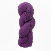 A skein of Plymouth Select Worsted Merino Superwash from Plymouth Yarn Co., in a deep purple hue, is coiled into an oval shape. The soft, twisty texture, enhanced by the superwash treatment, makes it perfect for knitting or crocheting projects. The plain white background highlights the rich color and impeccable stitch definition of this high-quality yarn.