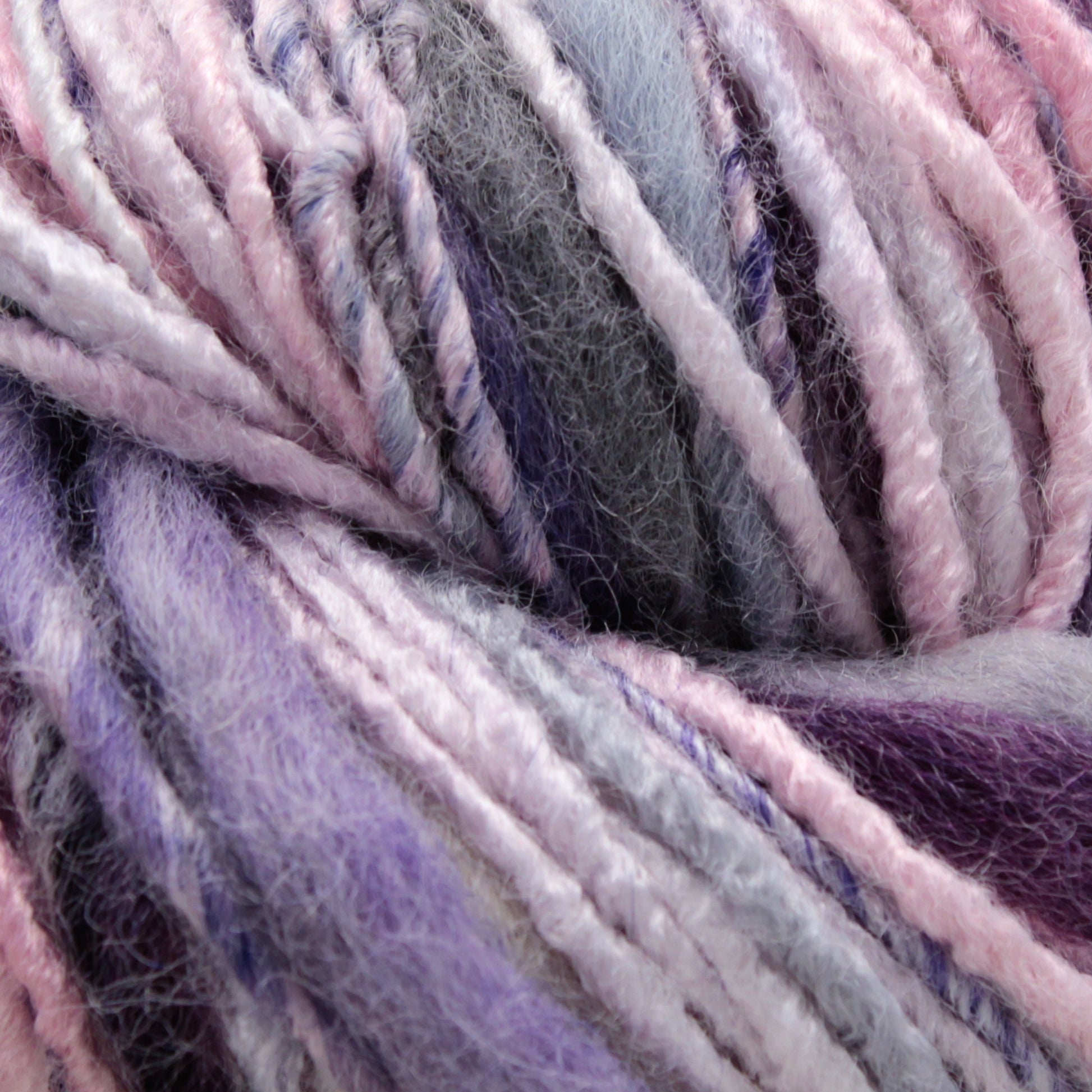 Close-up image of multi-colored yarn featuring shades of pink, purple, and grey intertwined together. The Bamboo Bloom Handpaints yarn from Universal Yarns appears soft and fluffy, with a slightly fuzzy texture.