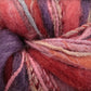 A close-up view of colorful yarn, featuring textures in shades of pink, purple, red, and blue intertwined. The fibers appear soft and fluffy like Universal Yarns' Bamboo Bloom Handpaints, showcasing different thicknesses and patterns of the strands.