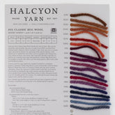 A sample card from Halcyon Yarn, labeled "001 Halcyon Classic Rug Wool - Desert Sunset," displays various strands of colorfast wool numbered from 1010 to 1280. It is titled "Classic Rug Wool Sample Card" and features contact information including a phone number and website at the top.