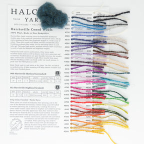 The Harrisville Fiber for Felting and Spinning - Sample Card from Halcyon Yarn showcases a variety of Harrisville Coned Wools paired with beautiful wool roving. The card features color codes beside small yarn samples, spanning neutral hues like white and gray to bright shades such as red, green, and blue. A dark blue ball of wool sits on top for an extra touch.