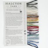 The Alafoss Icelandic Lopi Sample Card from Halcyon Yarn features 19 different yarn colors, each labeled with a corresponding number and name. The texture and appearance of the yarn varieties like Alafoss Lopi are clearly displayed. Additionally, there is a description highlighting the warm and durable characteristics of the fiber along with its recommended uses.