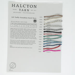 The Tuffy Sock Sample Card from Halcyon Yarn showcases 16 swatches of the 127 Tuffy Sock Yarn by Briggs & Little, featuring a variety of colors such as white, grey, black, and shades of blue and pink. Each swatch is labeled with a unique code and name. The accompanying text offers detailed information on the yarn's composition and care instructions.