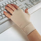 A person wearing beige Handeze Therapeutic Gloves by Berroco, Inc. is typing on a white keyboard. The fingerless Lycra gloves cover their wrist and part of their hand, providing arthritis relief while leaving the fingers exposed. The person has neatly manicured nails with nude polish.