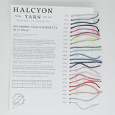 The Jo Sharp - Mulberry Silk Georgette Sample Card from Halcyon Yarn showcases 18 colors of opulent Mulberry Silk Georgette yarn, displayed as small strands. Each color is labeled with a name and number, and the card provides information on the yarn’s composition and care instructions for convenient reference.