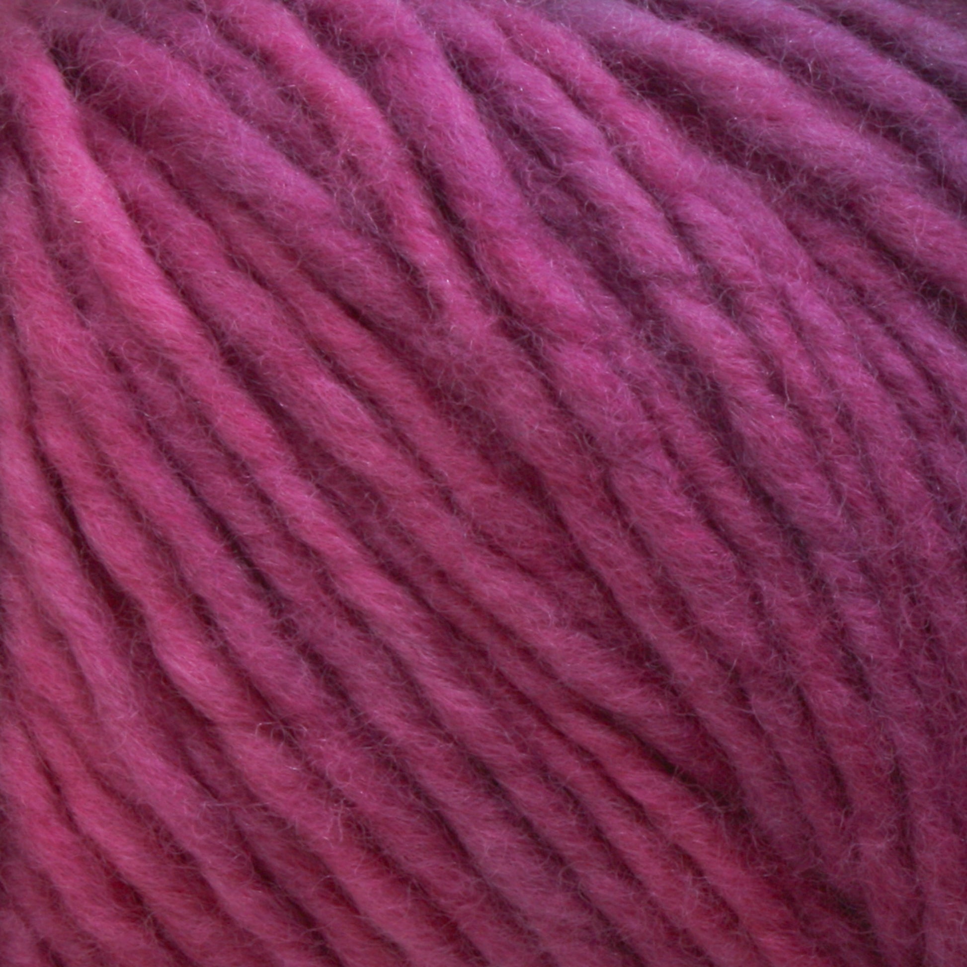 Close-up image of thick strands of pink and purple Malabrigo Merino Worsted Wool Yarn from Malabrigo Yarn that are twisted together, creating a textured pattern. The kettle-dyed colors blend seamlessly, offering a soft and cozy appearance suitable for knitting or crocheting projects with a worsted weight gauge.