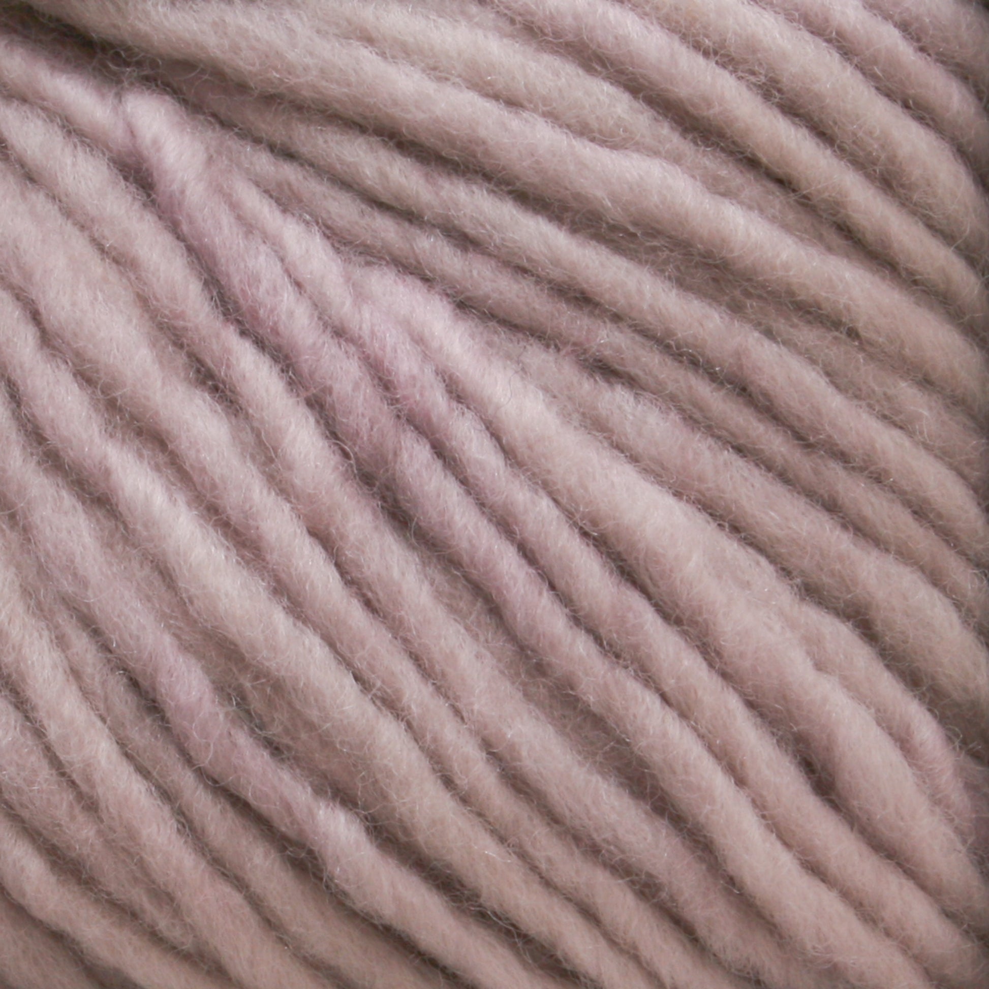 Close-up of soft, chunky, pink Malabrigo Merino Worsted Wool Yarn from Malabrigo Yarn with a slightly fuzzy texture, showing tightly stacked strands running parallel to each other. The yarn appears plush and thick, kettle-dyed to perfection, suitable for knitting or crocheting cozy items.