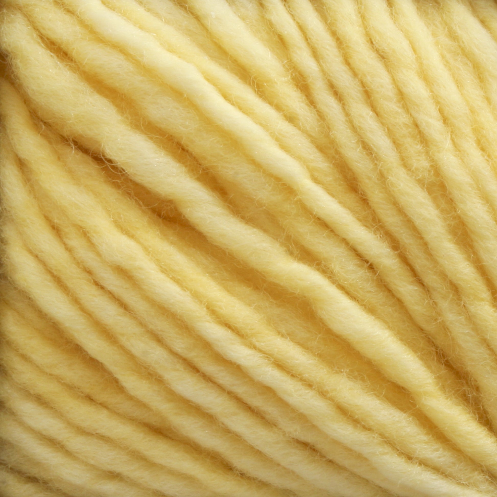 Close-up of the soft, thick strands of Malabrigo Merino Worsted Wool Yarn in a warm yellow shade, tightly wound together. The fuzzy and slightly uneven texture gives it a cozy and inviting appearance, making it perfect for knitting or crafting projects. Expertly kettle-dyed by Malabrigo Yarn for rich color depth and featuring a worsted weight gauge ideal for versatile creations.