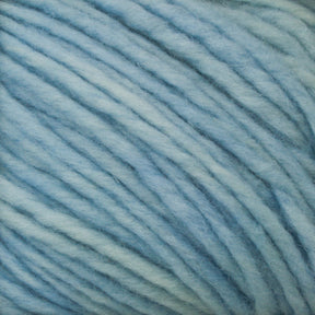 Close-up image of Malabrigo Merino Worsted Wool Yarn in light blue. The texture and individual strands of the thick, wool-like yarn are clearly visible, showcasing soft, subtle variations in the kettle-dyed blue color. The fluffy yarn from Malabrigo Yarn is ready for knitting or crafting projects at a worsted weight gauge.