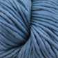 A close-up view of a ball of Malabrigo Merino Worsted Wool Yarn in a muted blue color. The strands of the Malabrigo Yarn kettle-dyed yarn are loosely wound, creating a cozy and textured appearance.