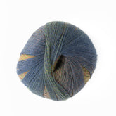 A skein of Knitting Fever Painted Desert Yarn from Euro Yarns, featuring super fine weight in various shades of blue, green, and muted rainbow tones, coiled neatly into a ball against a white background, perfect for lightweight accessories.