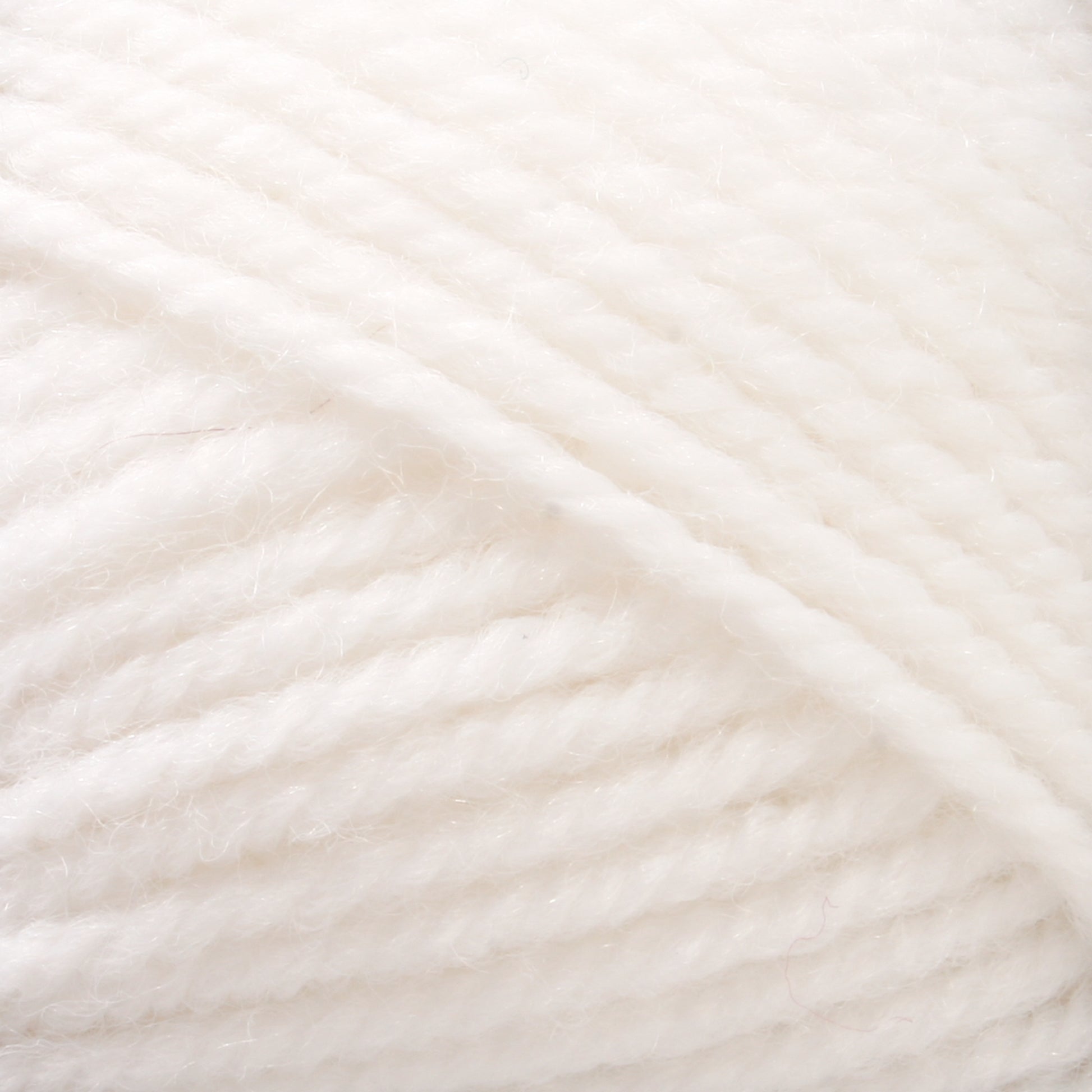 Close-up of a ball of Plymouth Encore Worsted Yarn by Plymouth Yarn Co. The worsted weight yarn is tightly wound, showcasing its soft, fluffy texture with visible fibers. The image highlights the details of the twisted strands and the even, consistent pattern of the winding, making it an economical option for various knitting projects.