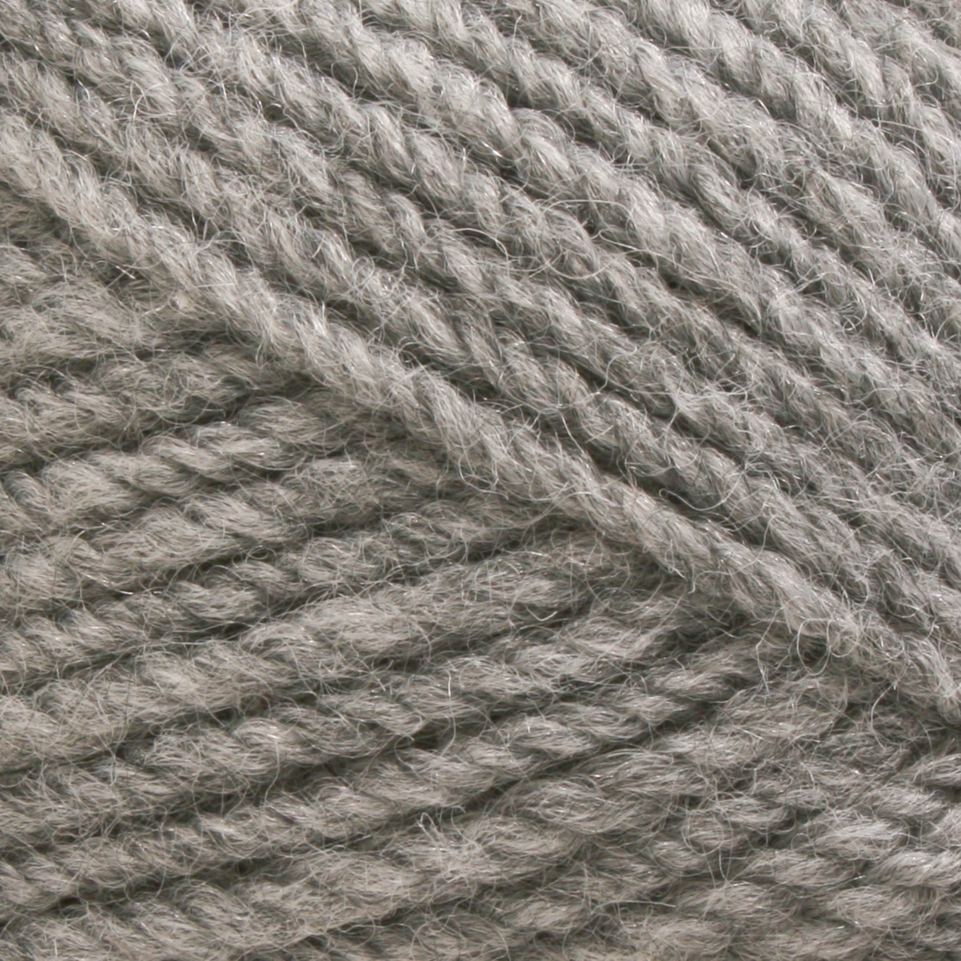 A close-up image of Plymouth Encore Worsted Yarn from Plymouth Yarn Co. reveals the soft, fibrous texture of the tightly wound threads. The light grey, natural fibers appear slightly fuzzy, making the yarn look plush and suitable for knitting or crocheting cozy garments and accessories.