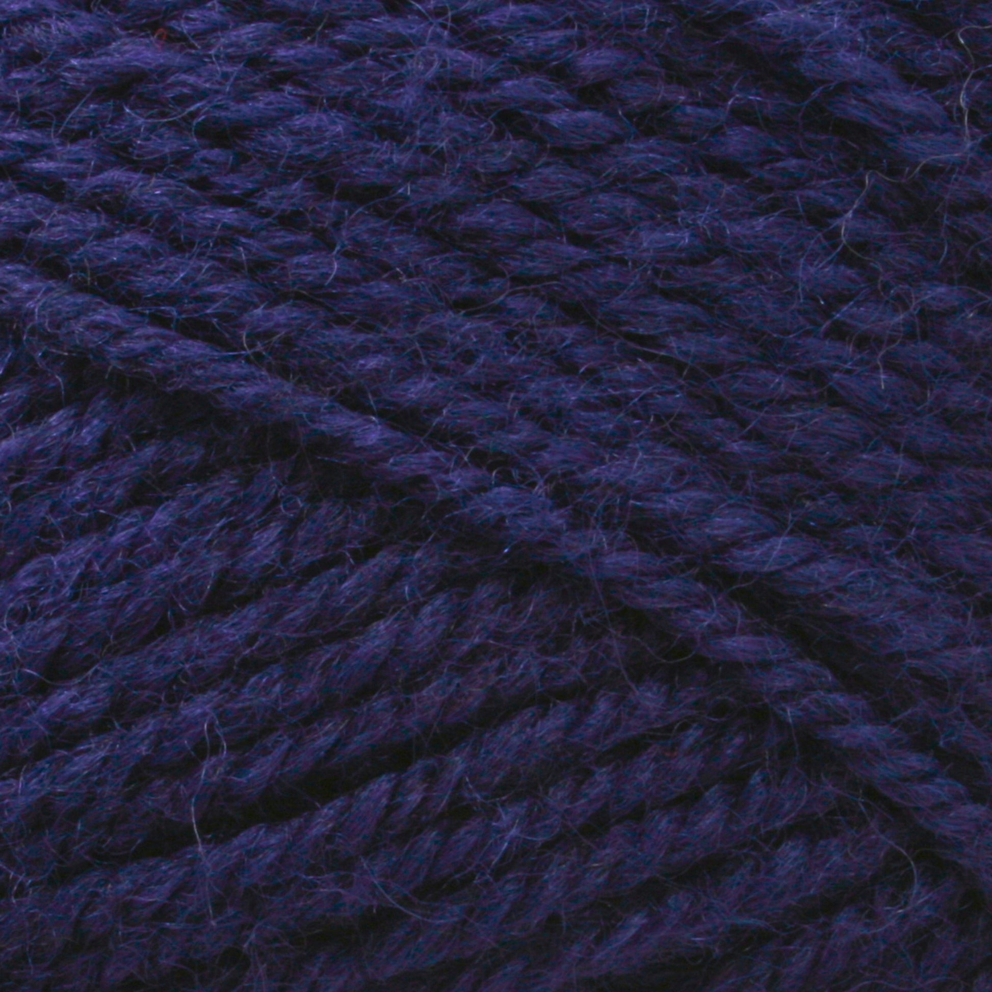 A close-up image of thick, dark purple Plymouth Encore Worsted Yarn from Plymouth Yarn Co. The twisted fibers and textured surface are clearly visible, showcasing the yarn's rich color and intricate weave. This machine washable yarn is an economical option for all your crafting needs.