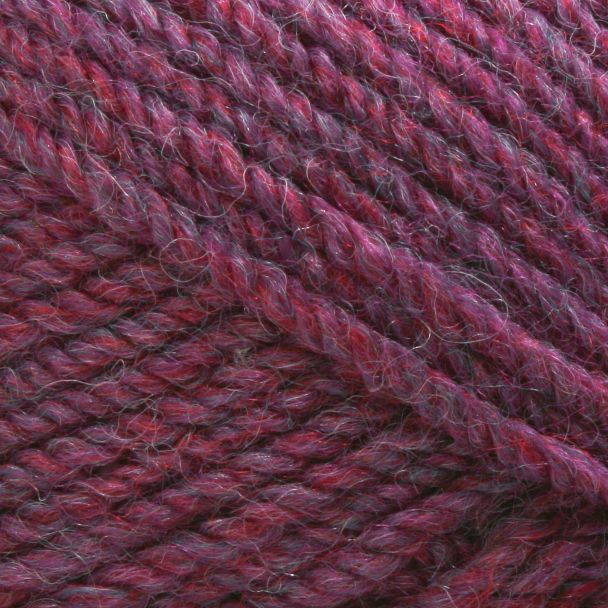 Close-up image of Plymouth Encore Worsted Yarn by Plymouth Yarn Co., showcasing thick, reddish-purple strands twisted into a soft, slightly fuzzy texture. The yarn features a mix of darker and lighter hues, making it an economical choice for any project.