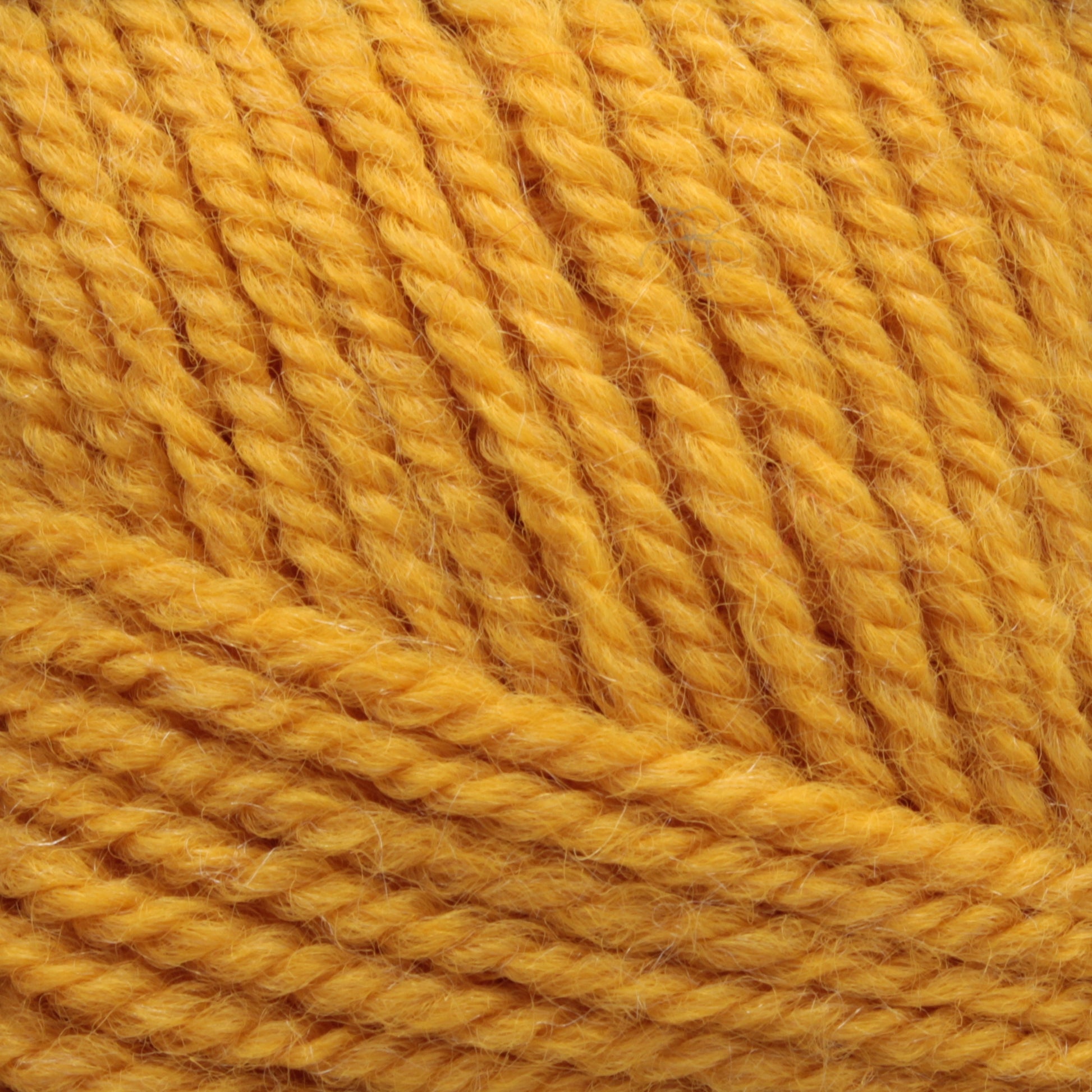 Close-up image of a ball of Plymouth Encore Worsted Yarn. The thick, soft fibers are tightly wound in a circular pattern, showcasing the texture and detail of the worsted weight yarn strands. This machine washable yarn from Plymouth Yarn Co. is an economical option for various knitting projects.