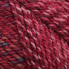 Close-up of Plymouth Encore Worsted Yarn by Plymouth Yarn Co., featuring a multi-colored, machine washable texture with shades of red, pink, blue, and beige. This soft and thick yarn showcases the intertwined strands of various hues in worsted weight, creating a visually rich and detailed pattern.