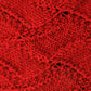 A close-up of the Peruby Waves Throw from Halcyon Yarn, showcasing its red knitted fabric with a textured, interlocking diamond pattern. The uniform stitches highlight the intricate wave stitch pattern and craftsmanship. The material appears warm and cozy, ideal for winter garments like sweaters or blankets made with chunky yarn.