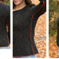 A person wearing a Halcyon Yarn's Hearthstone Cabled Pullover Pattern sweater in dark gray, crafted with DK wool and accented by an orange side seam. The textured design showcases diagonal lines, with photos capturing the front, back, and side views against a backdrop of autumn leaves.