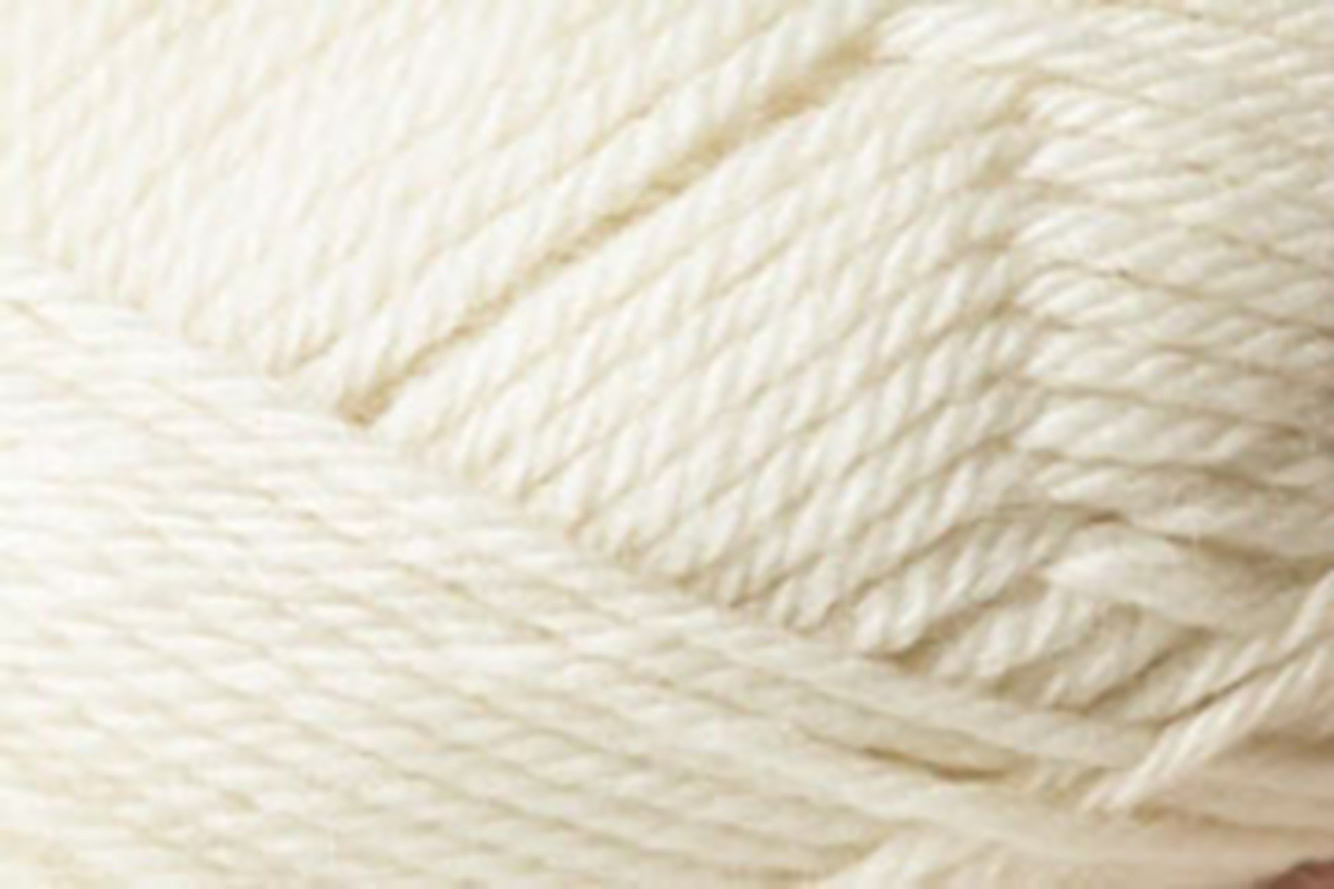 A close-up image of Jo Sharp Classic DK Wool by Kingfisher Yarn & Fibre. The tightly wound cream-colored strands reveal the texture and thickness of the premium-grade wool fibers, showcasing their soft and smooth appearance. The image captures the intricate details and natural warmth of this versatile DK gauge yarn.