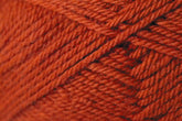 Close-up image of tightly wound, rust-colored yarn. The yarn's texture is prominent, showcasing its fibrous, twisted strands arranged in a diagonal pattern within the skein. This is Kingfisher Yarn & Fibre's Jo Sharp Classic DK Wool, perfect for your finest knitting projects.