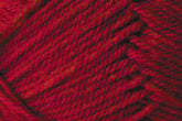 Close-up image of red yarn with visible fibers and strands twisted together, showing a textured pattern. The yarn appears soft and tightly spun, ideal for knitting or crocheting projects. This Jo Sharp Classic DK Wool by Kingfisher Yarn & Fibre showcases a vibrant red with subtle variations in shade, perfect for versatile DK gauge creations.