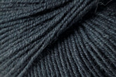 Close-up of Jo Sharp Mulberry Silk Georgette Yarn by Kingfisher Yarn & Fibre, showcasing detailed fibers and strands woven together. The yarn, in a dark grey hue, appears soft and slightly hairy, making it ideal for knitting or crocheting heirloom projects. The image captures the intricate details and depth of this extrafine Merino wool blend yarn.