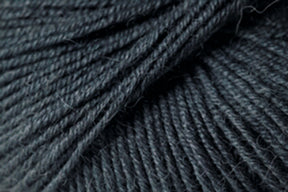 Close-up of Jo Sharp Mulberry Silk Georgette Yarn by Kingfisher Yarn & Fibre, showcasing detailed fibers and strands woven together. The yarn, in a dark grey hue, appears soft and slightly hairy, making it ideal for knitting or crocheting heirloom projects. The image captures the intricate details and depth of this extrafine Merino wool blend yarn.