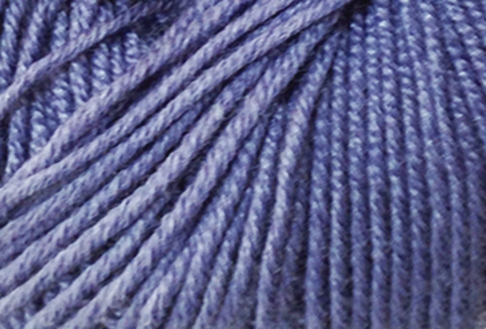 Close-up image of a ball of lavender-colored Jo Sharp Mulberry Silk Georgette Yarn from Kingfisher Yarn & Fibre, with tightly wound strands. The texture of the yarn is clearly visible, showcasing a soft and slightly shiny appearance, reminiscent of heirloom items crafted with Extrafine Merino Wool.