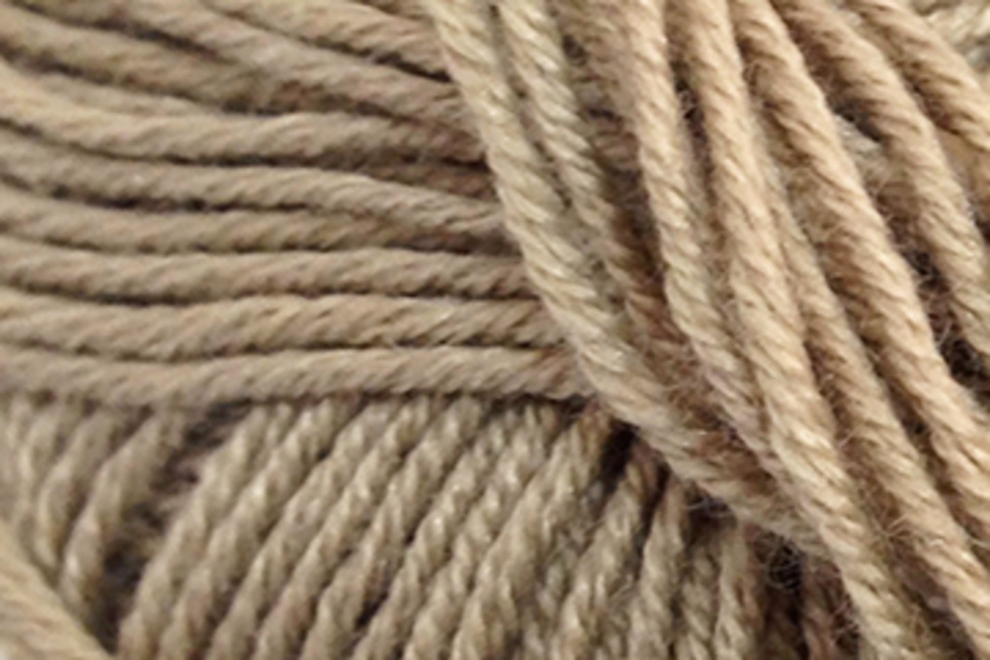 Close-up image of beige yarn strands wound together, showcasing the texture and twist of the extrafine Merino wool fibers from Jo Sharp Mulberry Silk Georgette Yarn by Kingfisher Yarn & Fibre.