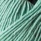 Close-up of soft, light teal yarn, showcasing its texture and tightly wound strands. The image highlights the yarn's smooth and slightly fuzzy surface, suggesting its suitability for knitting or crocheting cozy garments or heirloom items made from Jo Sharp Mulberry Silk Georgette Yarn by Kingfisher Yarn & Fibre.