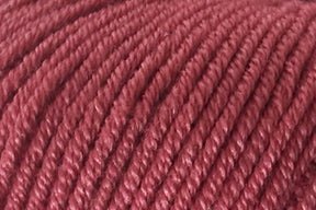 Close-up of a ball of Jo Sharp Mulberry Silk Georgette Yarn with a pinkish-red hue, crafted from soft Extrafine Merino Wool. The texture of the yarn fibers and individual strands are clearly visible, making it perfect for creating heirloom items by Kingfisher Yarn & Fibre.