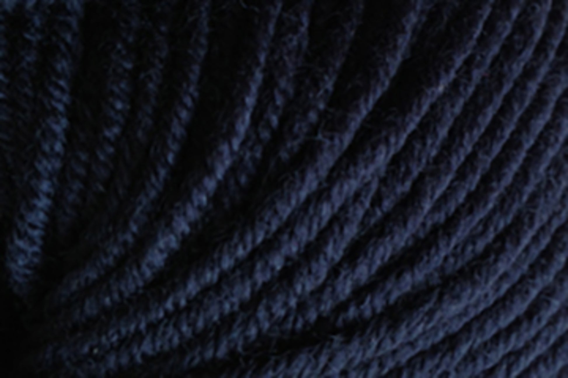 Close-up image of tightly coiled strands of dark blue Jo Sharp New Era Merino DK Superwash yarn from Kingfisher Yarn & Fibre, showcasing the texture and detail of the super soft, machine washable fibers.