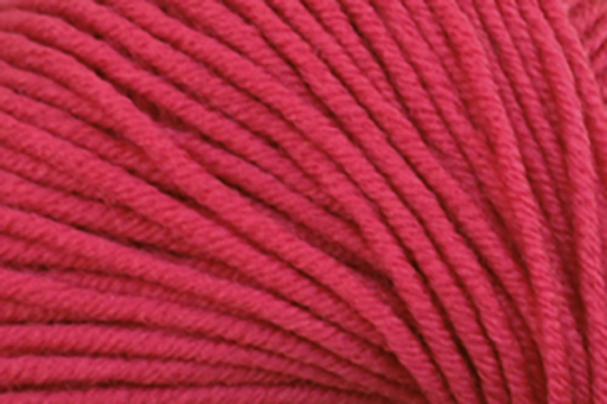 Close-up of Kingfisher Yarn & Fibre's Jo Sharp New Era Merino DK Superwash in bright red, showcasing its super soft yarn in tight loops with visible texture and fibers. The neatly wound strands make it perfect for DK weight projects, creating a pattern of parallel lines. The vibrant color remains consistent throughout the image.