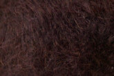 Close-up view of Jo Sharp Rare Comfort Kid Mohair from Kingfisher Yarn & Fibre, showcasing a dark brown, coarse, and curly textured material. The texture appears dense and fibrous, creating a rugged yet surprisingly soft appearance.