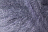 Close-up image showcasing the predominantly gray, woolly texture of Kingfisher Yarn & Fibre's Jo Sharp Rare Comfort Kid Mohair, with subtle hints of purple and black. The dense and slightly tangled fibers create a soft, fuzzy appearance that promises rare comfort.