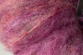 Close-up of fluffy, textured pink and purple Kid Mohair fibers from the Jo Sharp Rare Comfort collection by Kingfisher Yarn & Fibre, intertwined to showcase a range of shades with a slightly fuzzy appearance. Perfect for crafting airy sweaters that epitomize rare comfort.