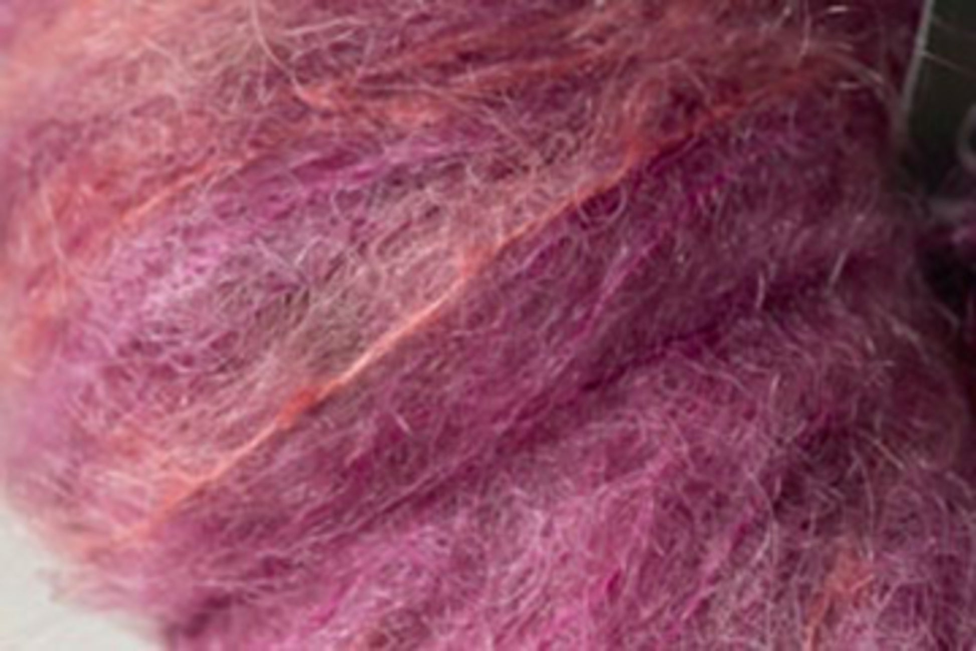 Close-up of fluffy, textured pink and purple Kid Mohair fibers from the Jo Sharp Rare Comfort collection by Kingfisher Yarn & Fibre, intertwined to showcase a range of shades with a slightly fuzzy appearance. Perfect for crafting airy sweaters that epitomize rare comfort.