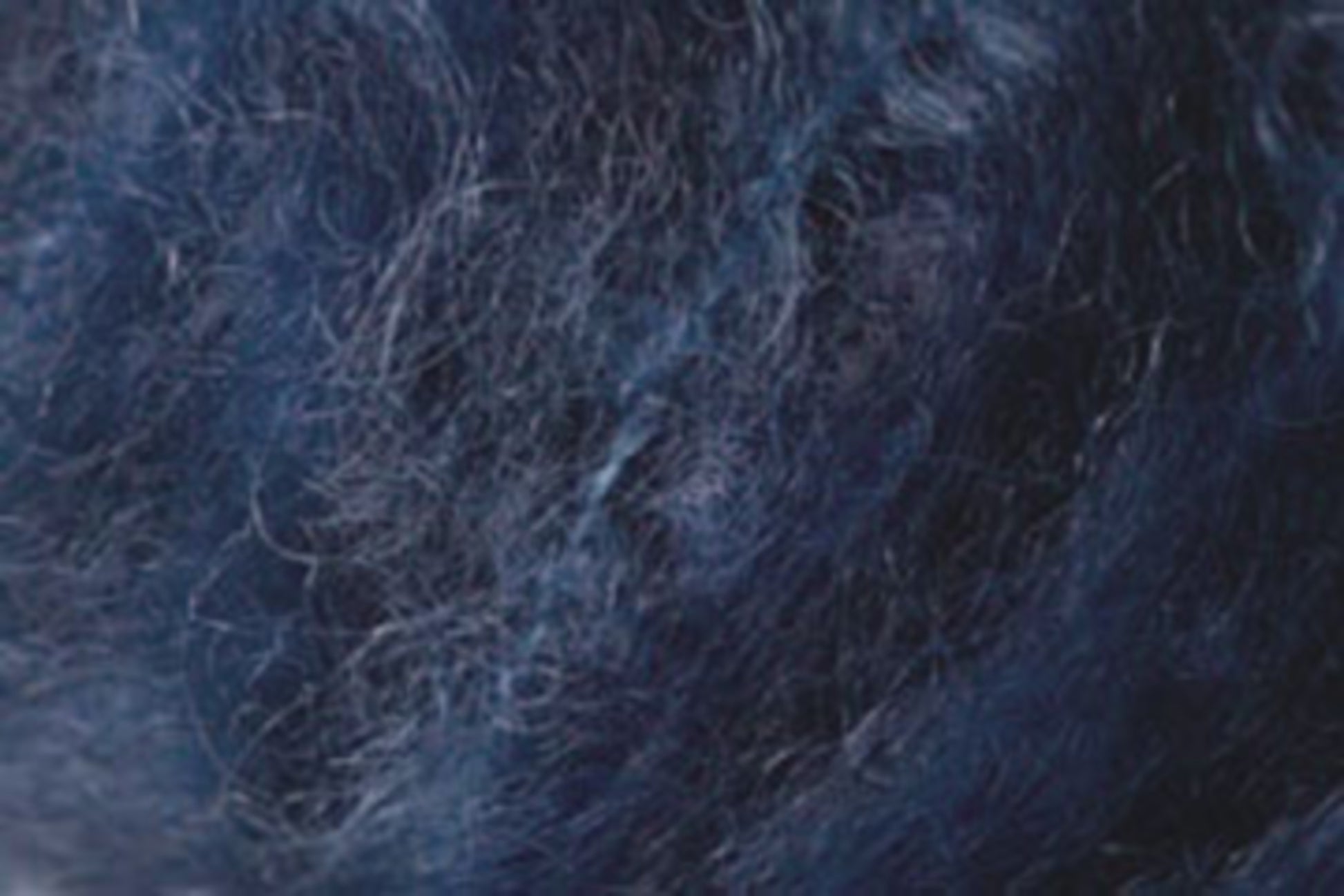 Close-up image of Jo Sharp Rare Comfort Kid Mohair by Kingfisher Yarn & Fibre, showcasing a dark blue and black textured surface. The fine, intertwined fibers create a slightly tangled appearance reminiscent of airy sweaters. The texture features a mix of light and dark shades, highlighting the material's depth and complexity.